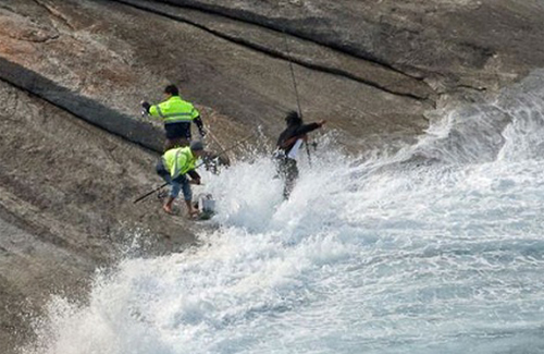 Fishers get swamped by wave on rocks